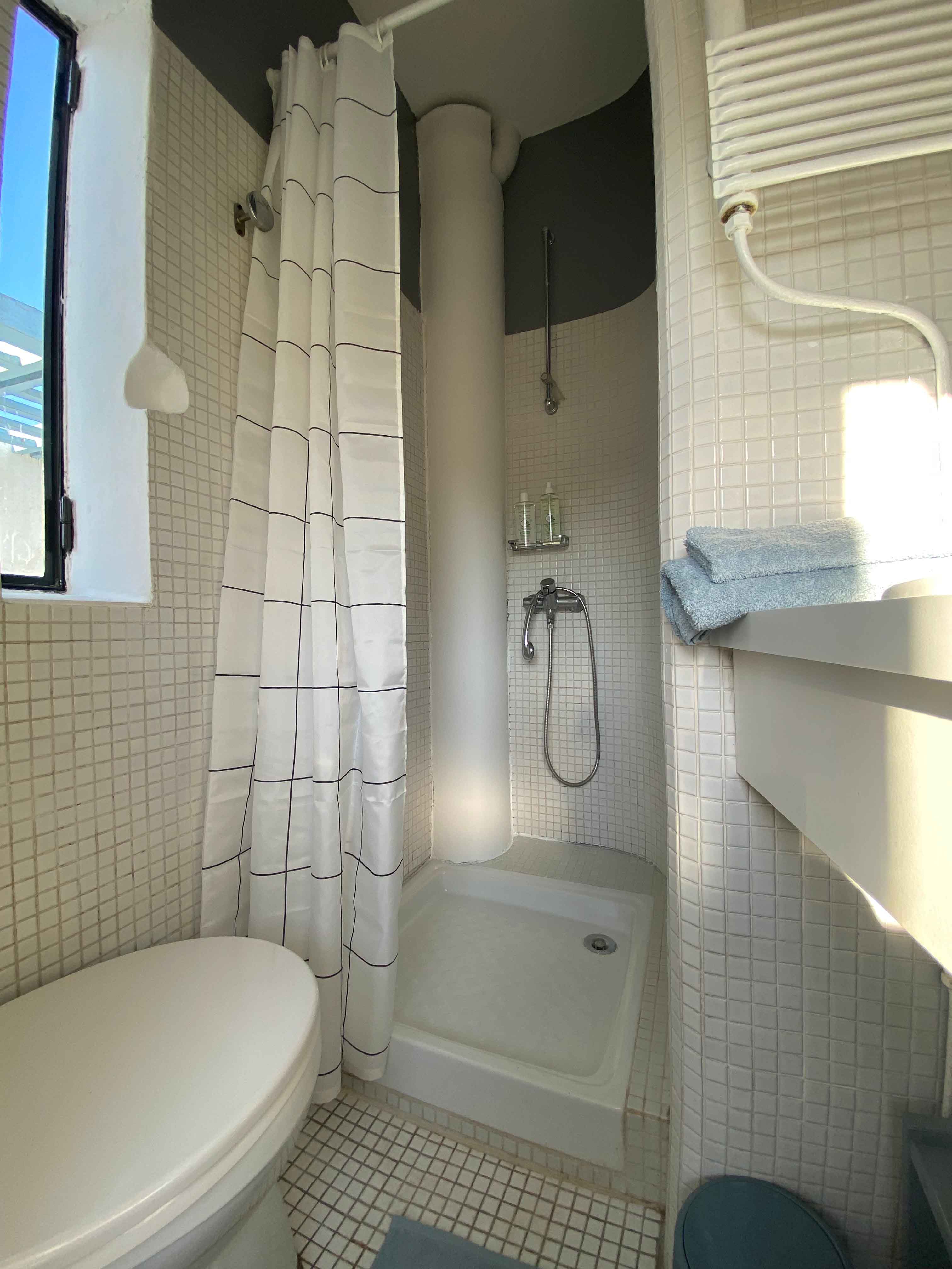 Salle de bain avec douche carrelée et rideau à carreaux